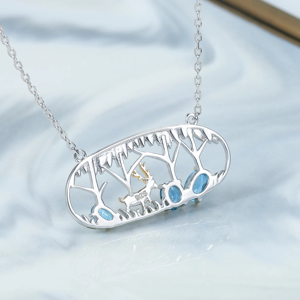 Blue Antler Swiss blue topaz deer pendant on pale marble