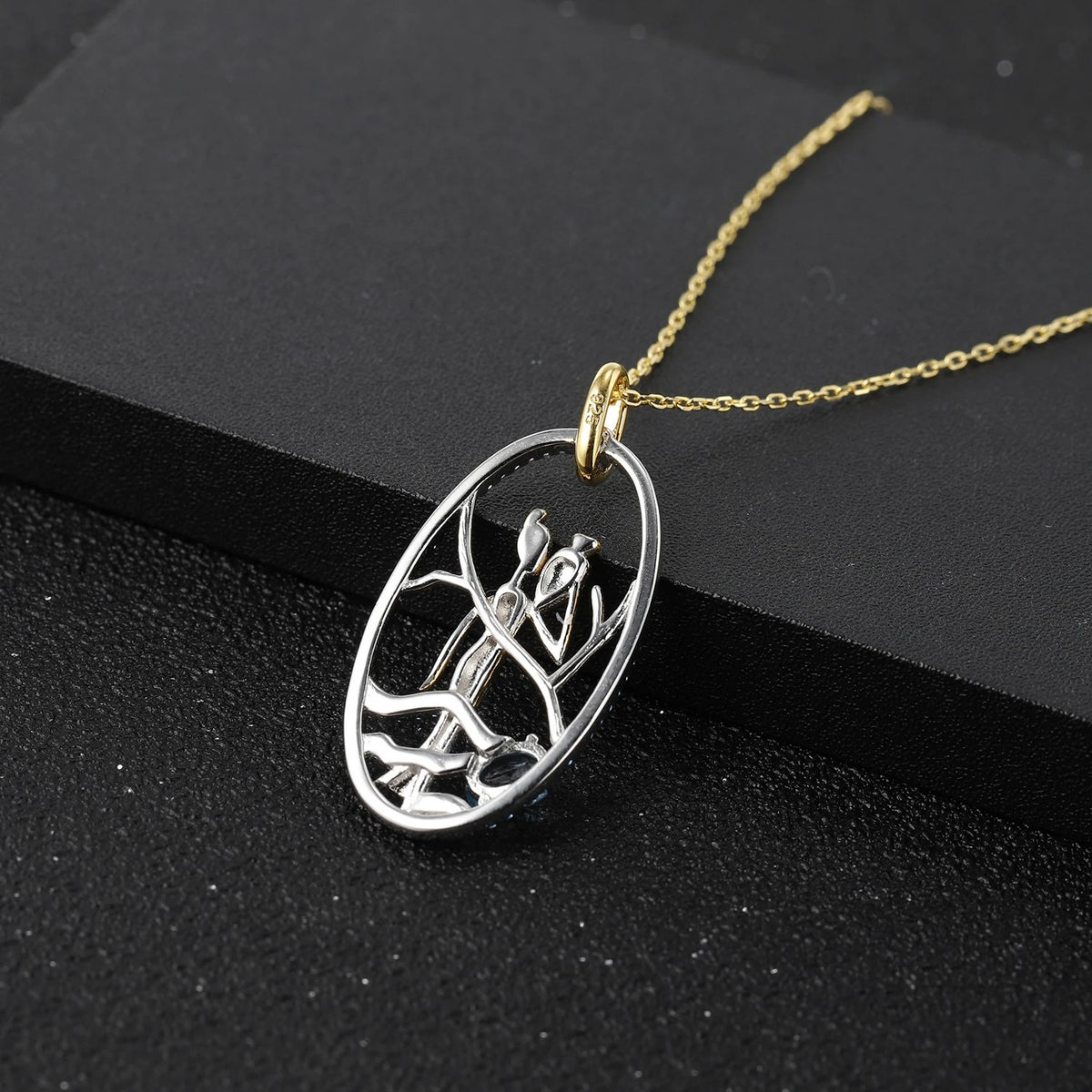 Blue Trace diffusion sapphire pendant, pierced silver oval on a dark ground