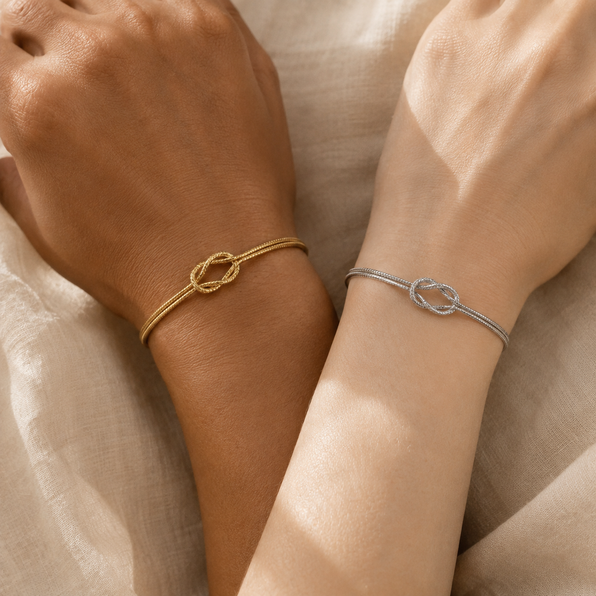 Two people wearing The Tie gold and silver knot bracelets together